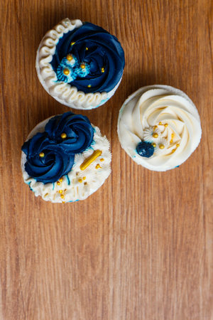 Luxurious and elegant cupcakes, with white cream and navy blue with gold sprinkles. It has a sweet and creamy taste.の写真素材