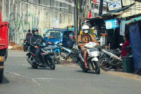 Jakarta, Indonesia in November 2022. Front view of a motorcyclist driving on a busy street on the...
