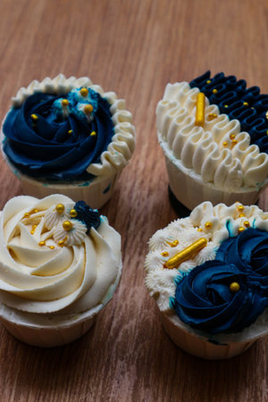 Luxurious and elegant cupcakes, with white cream and navy blue with gold sprinkles. It has a sweet and creamy taste.の写真素材