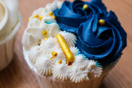 Luxurious and elegant cupcakes, with white cream and navy blue with gold sprinkles. It has a sweet and creamy taste.の写真素材