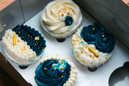 Luxurious and elegant cupcakes, with white cream and navy blue with gold sprinkles. It has a sweet and creamy taste.の写真素材