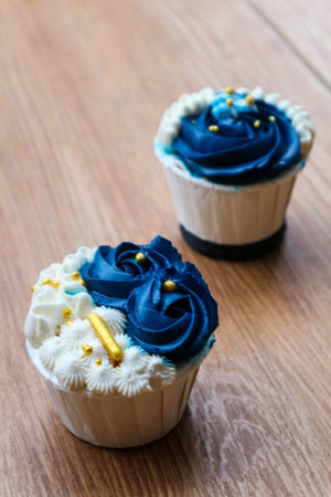 Luxurious and elegant cupcakes, with white cream and navy blue with gold sprinkles. It has a sweet and creamy taste.の写真素材