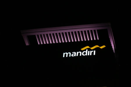 Bekasi, Indonesia in July 2022. The logo of Bank Mandiri shining brightly at night against the dark night sky. Bank Mandiri is one of the largest banks in Indonesia in terms of total assets, loans and deposits.のeditorial素材