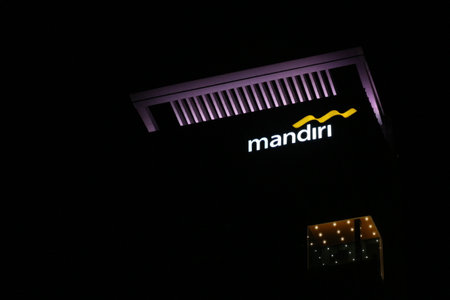 Bekasi, Indonesia in July 2022. The logo of Bank Mandiri shining brightly at night against the dark night sky. Bank Mandiri is one of the largest banks in Indonesia in terms of total assets, loans and deposits.のeditorial素材