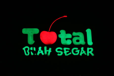 Bekasi, Indonesia in July 2022. The TOTAL Buah Segar logo shining brightly at night against the dark night sky. Total fresh fruit is a big fruit shop that is famous in Indonesia because it provides many types of fruit.のeditorial素材