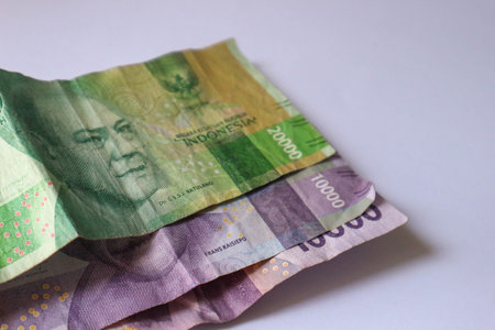 Isolated white photo of three rupiah banknotes. This money consisted of two ten thousand bills and...