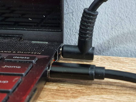 A laptop that is being charged, Laptop connected with power supply cable charger, where the port for...