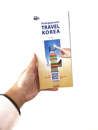 Jakarta, Indonesia in May 2022. A hand is holding a welcome guide book for travelers on vacation on Korea. The back page contains an advertisement for the KOREA TRAVEL BOOKS application.のeditorial素材