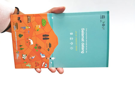 Jakarta, Indonesia in May 2022. A hand is holding a welcome guide book for travelers on vacation on...