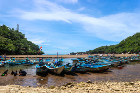 Yogyakarta, Indonesia in October 2022. Local tourists enjoying Baron beach, Gunung Kidul. They boarded a blue tour boat to circle this beach.のeditorial素材