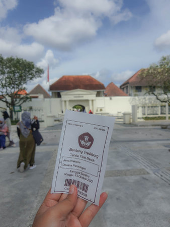 Yogyakarta, Indonesia in November 2022. A hand is holding a ticket to enter the Fort Vredeburg Museum, with the background behind it is the entrance to Fort Vredeburg. Previously this building served as one of the Dutch defense tools. There, the Dutch monのeditorial素材