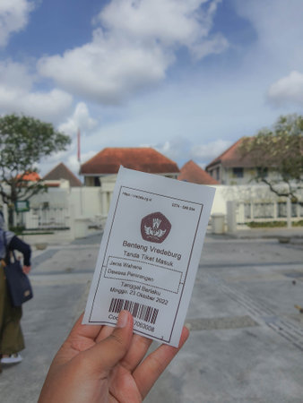 Yogyakarta, Indonesia in November 2022. A hand is holding a ticket to enter the Fort Vredeburg Museum, with the background behind it is the entrance to Fort Vredeburg. Previously this building served as one of the Dutch defense tools. There, the Dutch monのeditorial素材