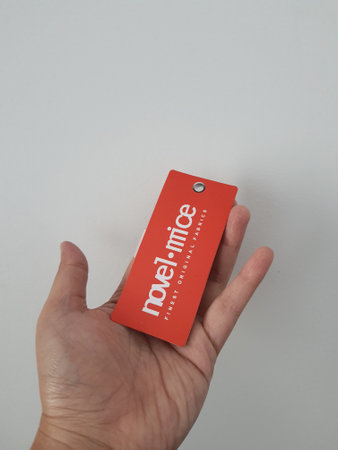 Bekasi, Indonesia in May 2022. A hand holds a tag from an Indonesian clothing brand, Novel Mice. With a red tag color and white writing.のeditorial素材