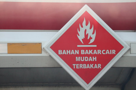 A warning sign for a fuel tank, namely a combustible fuel sign, made of a rhombus-shaped steel plate affixed with a reflective sticker with a red base and white lines and writingの写真素材