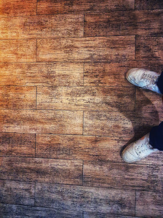 A pair of white shoes on a floor with a wooden texture. Copy space, negative space. Perfect for your templates.の写真素材