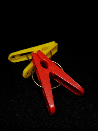 Isolated photo of clothespins in red and yellow with very contrasting colors. With a black background.の写真素材