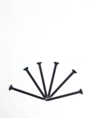 An isolated white photo of six black bolts with sharp edges that will be used to mount a shelf on the wall.の写真素材