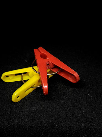 Isolated photo of clothespins in red and yellow with very contrasting colors. With a black background.の写真素材