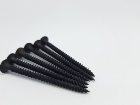 An isolated white photo of six black bolts with sharp edges that will be used to mount a shelf on the wall.の写真素材