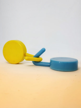 Two round blue and yellow clothes hook hangers that go hand in hand. Isolated white's photo.の写真素材