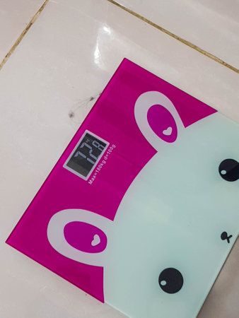 A pink and white weight scale with a picture of a cute rabbit. The led screen shows a person's weight of 72.8 kg.の写真素材