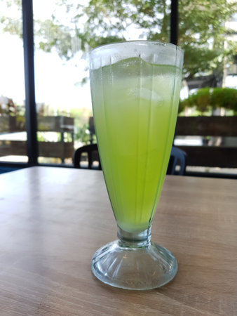 A glass of iced melon lemonade. Fresh orange juice with sweet melon syrup. A very delicious and refreshing blend to drink on a hot day. This ice is green.の写真素材