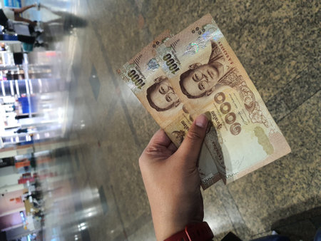 A hand is holding two thousand baht bills. Baht is the state currency of Thailand.の写真素材