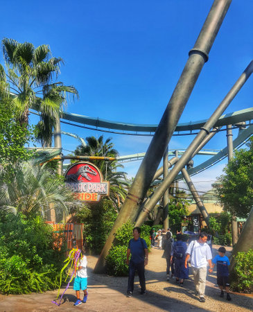 Osaka, Japan on September 30, 2023. Visitors to Universal Studios Japan are passing under the track of the Jurassic Park The Flying Dinosaur roller coaster. This incredibly long, state-of-the-art flying coaster features unimaginable ascents and drops.のeditorial素材