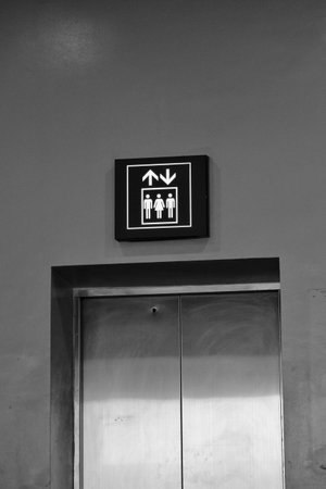 Elevator or lift sign board, with blue and white lines. There are 2 men and 1 woman in the form.
