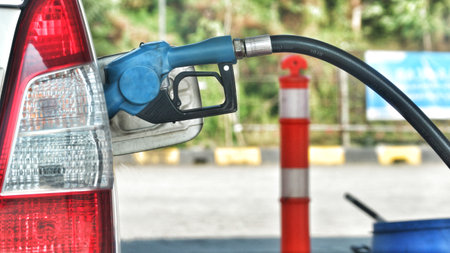 A white car is filling its gas tank at a gas station. The nozzle is blue.のeditorial素材