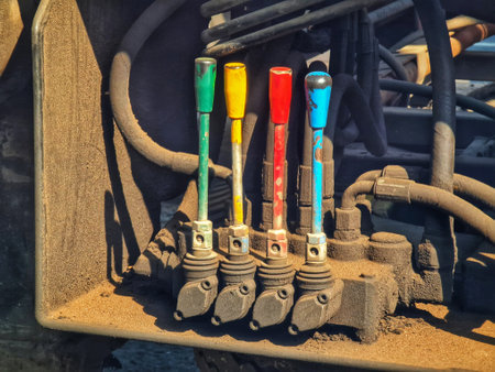 Sun-drenched industrial levers, painted in vibrant hues, stand out against a gritty, aged machine backdrop.  A captivating scene of weathered machinery.の写真素材