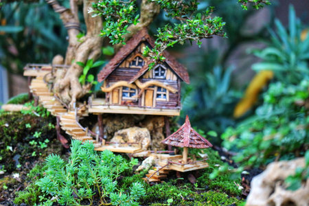 A charming miniature treehouse nestled in a lush bonsai, creating a peaceful and enchanting miniature world. Wooden details and vibrant green plants add to its whimsical charm.の写真素材
