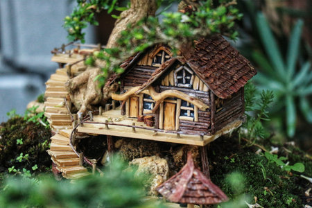 A charming miniature house nestled in a bonsai tree, wooden stairs winding up to its rustic door. The scene is peaceful and enchanting, a tiny world of detail.の写真素材
