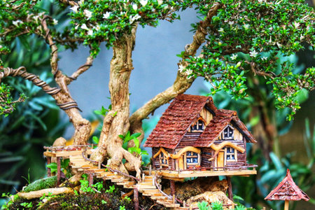 A charming miniature house sits on a whimsical wooden deck among a vibrant bonsai tree.  The scene is serene and enchanting, perfect for a quiet moment.の写真素材