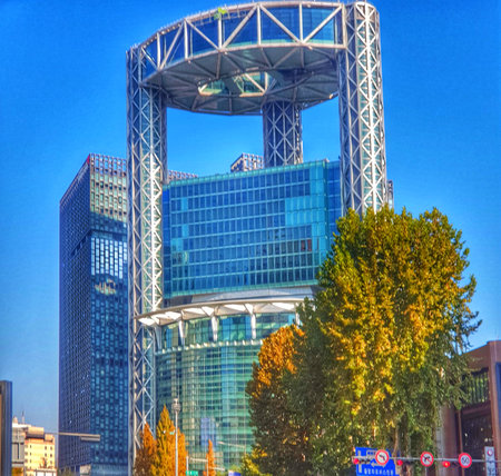 Seoul, South Korea on 12 Nov 2024. A striking glass tower dominates the cityscape, its modern design contrasted by the warm autumn foliage. Sunlight illuminates the scene, creating a vibrant and energetic mood.の写真素材