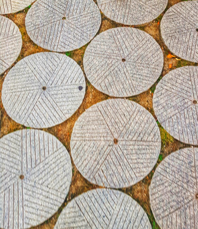 A calming view of a pathway paved with intricately carved granite circles.  The neutral tones and geometric patterns create a peaceful, almost meditative atmosphere.の写真素材