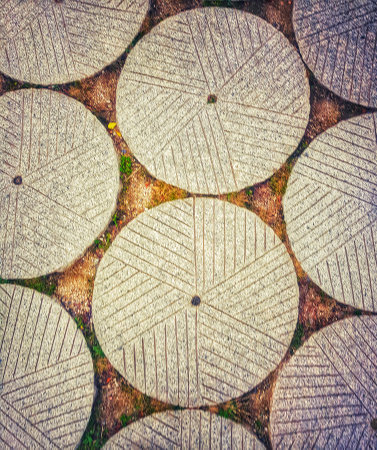 Intricate circular stone millstones create a rustic pavement.  The textured surface and earthy tones evoke a sense of history and calm.の写真素材