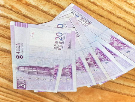 Macau, China on 14 Nov 2024. A captivating spread of Macau's twenty pataca banknotes rests on a warm wooden surface. The soft lighting enhances the purple hues, creating a serene yet valuable scene.の写真素材