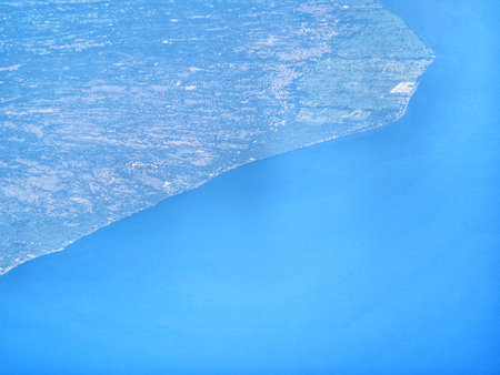 An aerial perspective shows land bordering the clear blue sea creating a distinct contrast great for geographical and travel themes.の写真素材