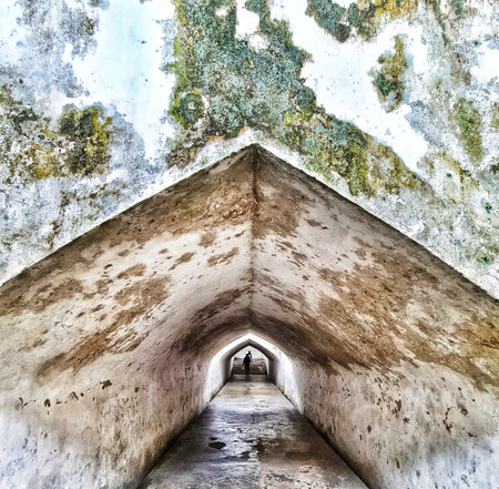 Yogyakarta, Indonesia on 22 Feb 2025. Person walking through a long ancient tunnel with textured walls and a unique architectural perspective, creating an intriguing travel or historical backdrop.の写真素材