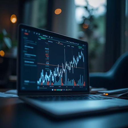 Laptop displays financial charts and graphs showing market trends ideal for business presentations or financial analysis, in a dimly lit room.の素材