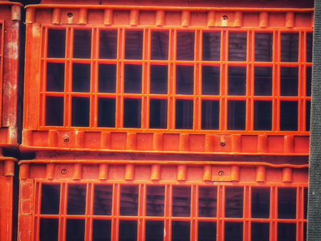 Stacked orange plastic crates create a geometric grid pattern with a strong sense of depth and texture, ideal for use in industrial or organizational themed marketing materials.の写真素材