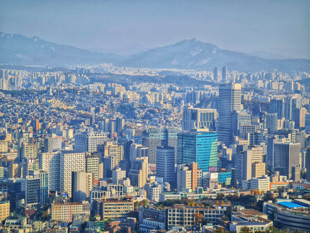 Seoul, South Korea on 11 Nov 2024. Extensive cityscape shows densely packed buildings and skyscrapers under a blue sky with distant mountains, conveying a busy yet serene atmosphere, suitable for travel or real estate marketing.のeditorial素材