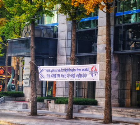 Seoul, South Korea on 11 Nov 2024. White banner hanging on trees in urban area with modern building, showcasing text and design, creating a sense of public sentiment for commercial use.のeditorial素材