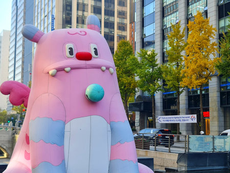Seoul, South Korea on 11 Nov 2024. Large inflatable pink monster sits in an urban cityscape, adding whimsy with light blue accents and toothy grin, set against modern buildings for fun marketing.のeditorial素材