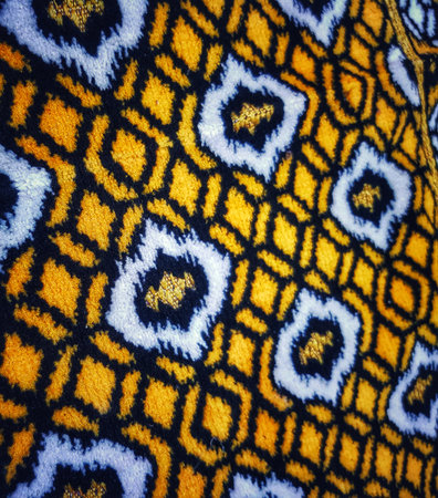 Geometric pattern features a close-up view of repeating yellow diamonds connected by black lines, interspersed with ornate white and gold shapes, ideal for abstract backgrounds or textured design elements.の写真素材