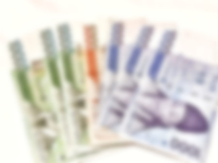 Blurred paper currency of various colors rests in a pile against a clean white background creating a sense of wealth and financial transaction for finance related imagery.の写真素材
