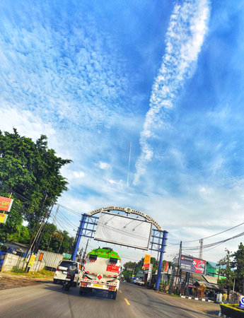 Cikampek, Indonesia on 20 nov 2025. Highway scene shows tanker truck and other vehicles moving toward a metal sign frame under a partly cloudy blue sky, suitable for travel and transportation marketing.のeditorial素材