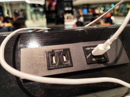 Tokyo, Japan on 20 Oct 2025. Haneda Airport. Power outlet shows white cable plugged into the usb power port in a public area, with dim lighting and blurred background, showcasing modern charging solutions in public spaces.のeditorial素材