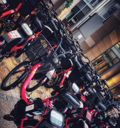 Tokyo, Japan on 20 Oct 2025. Multiple red and black bikes parked outdoors in front of a modern office building with glass windows and tiled pavement, creating an urban transportation scene perfect for travel or city lifestyle marketing.の写真素材